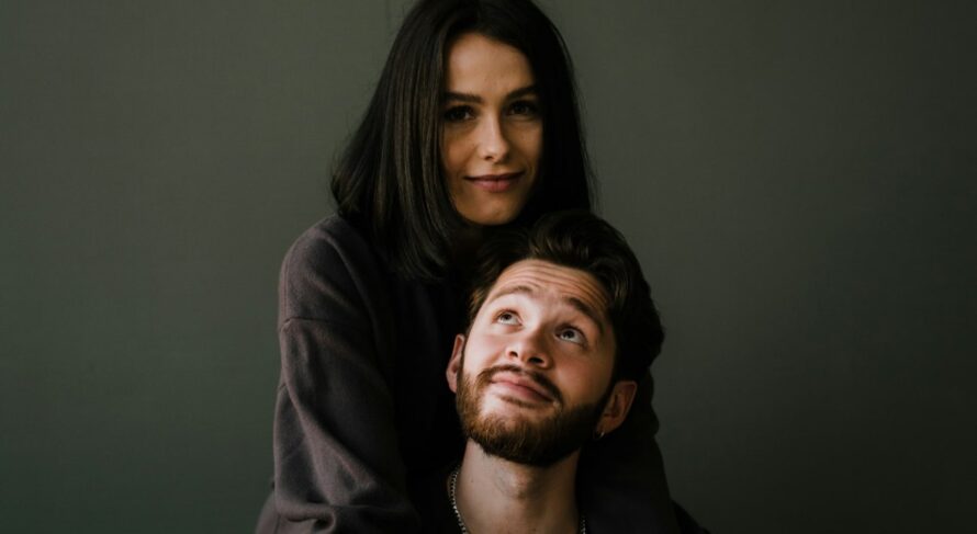 Intimate couple portrait against a deep green backdrop, showcasing warmth and connection.