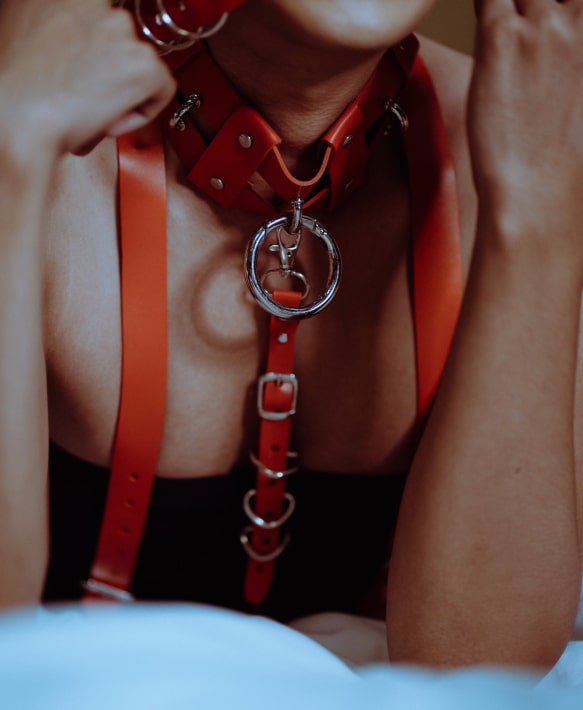 Bold red leather harness close-up showcasing individuality and self-expression in an intimate setting.