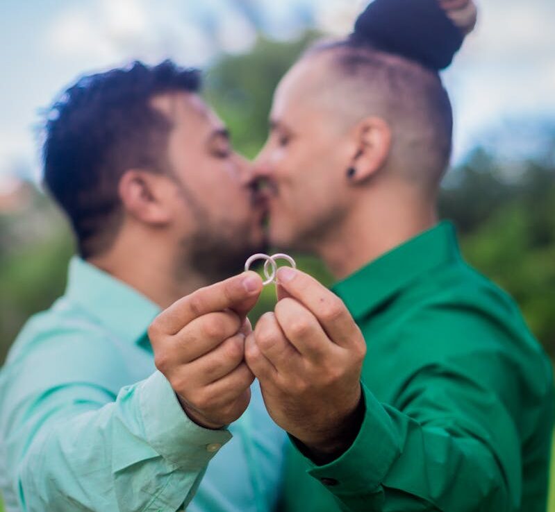 Una pareja de enamorados sujeta sus anillos de compromiso al aire libre, como muestra de afecto y compromiso.