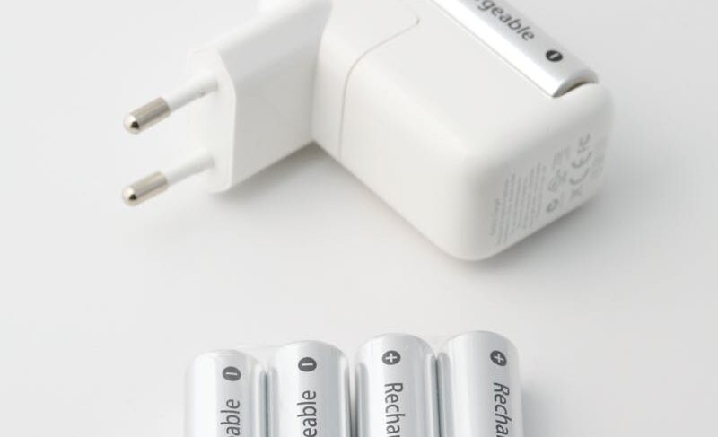 Close-up of a battery charger and rechargeable batteries on a white background, perfect for tech and energy themes.