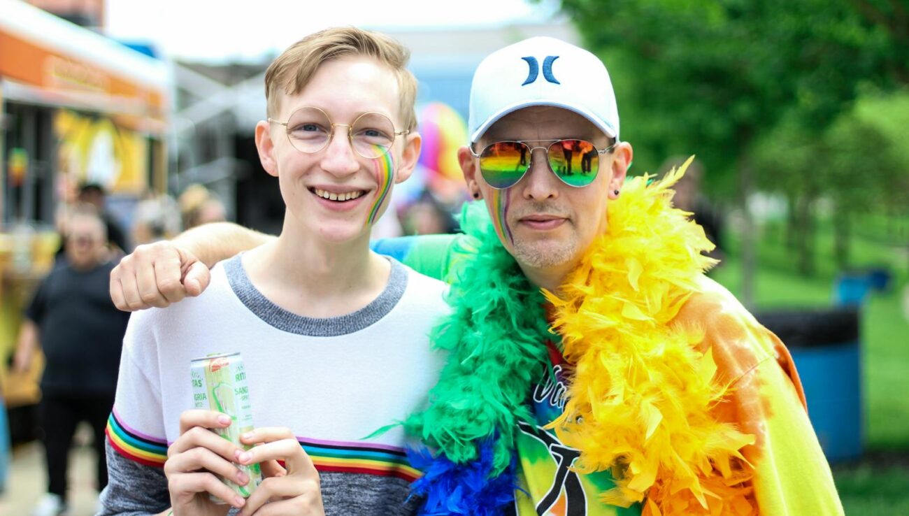 Deux personnes se sourient et s'embrassent lors d'un festival de la fierté en plein air aux couleurs de l'arc-en-ciel.