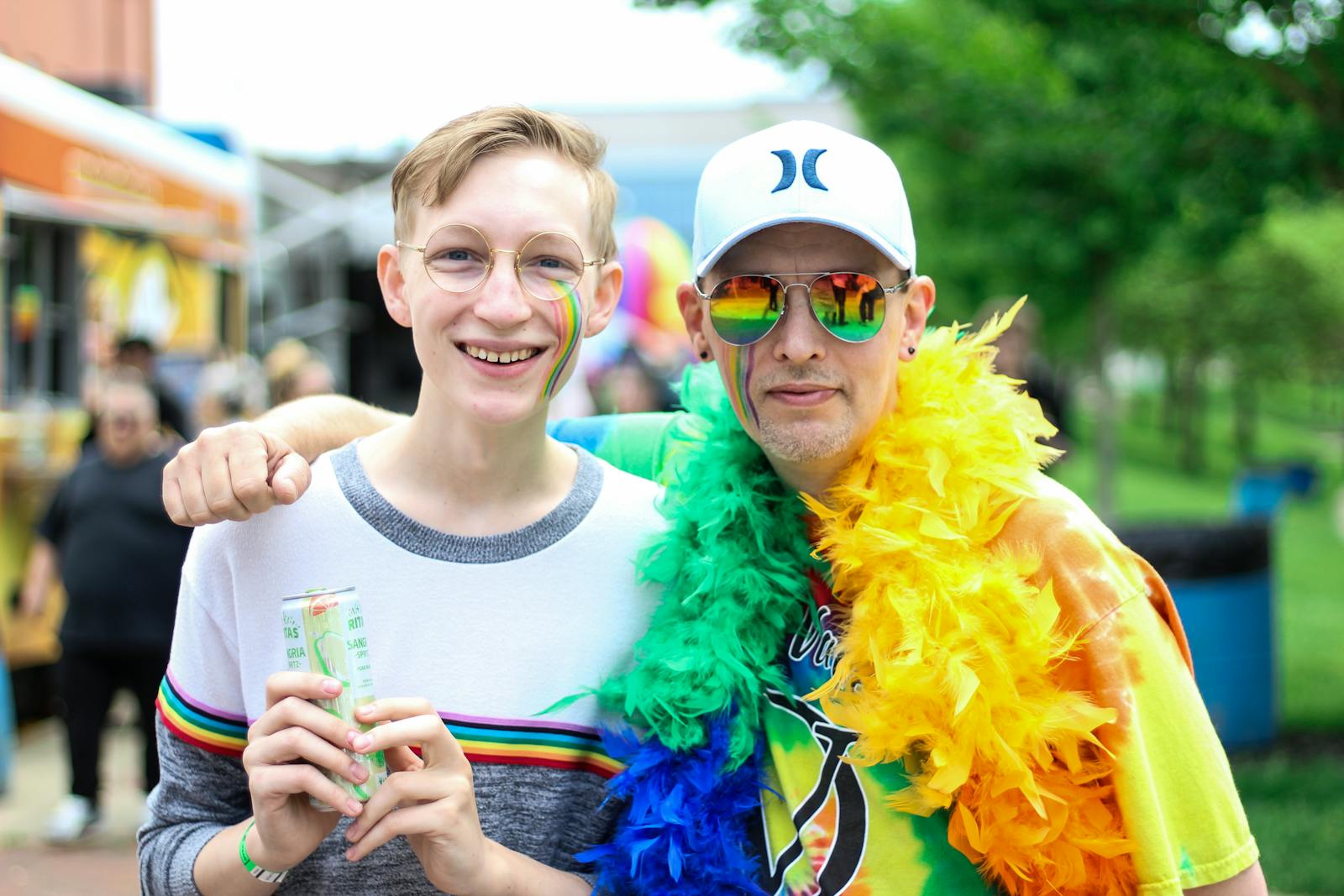 Deux personnes se sourient et s'embrassent lors d'un festival de la fierté en plein air aux couleurs de l'arc-en-ciel.