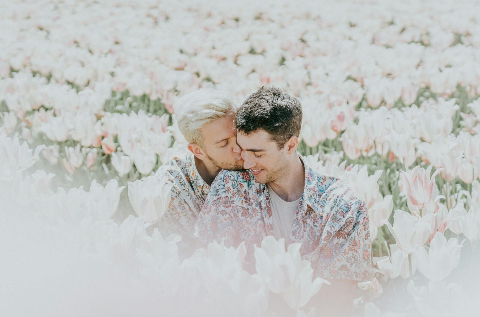 Una alegre pareja comparte un tierno momento en un campo de tulipanes iluminado por el sol.