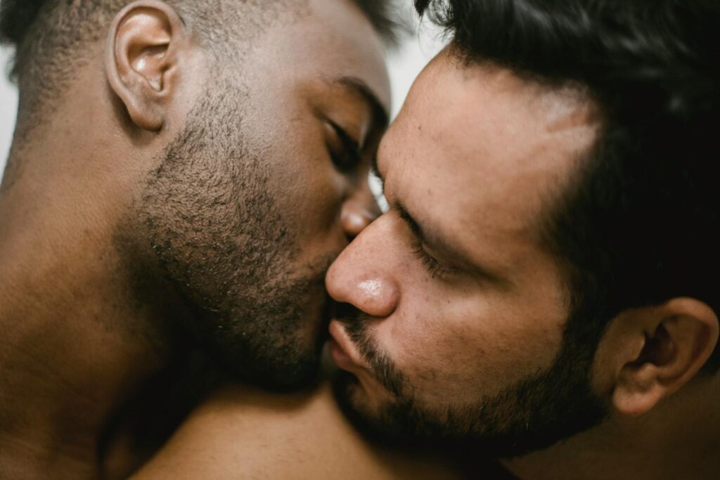 Close-up of an interracial gay couple sharing an intimate kiss, expressing love and togetherness.