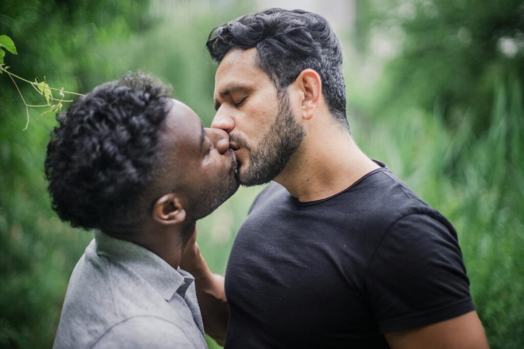 Intimate outdoor kiss between interracial gay couple expressing love and affection.