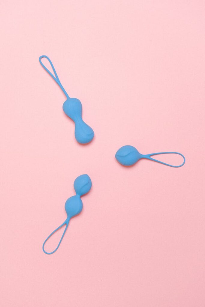 Three blue silicone geisha balls arranged on a pink background, top view.