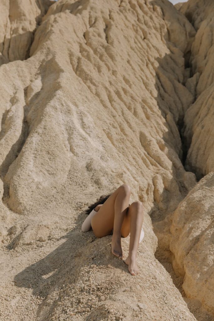 Uma mulher deita-se descalça numa colina de areia, captando um momento sereno de verão.