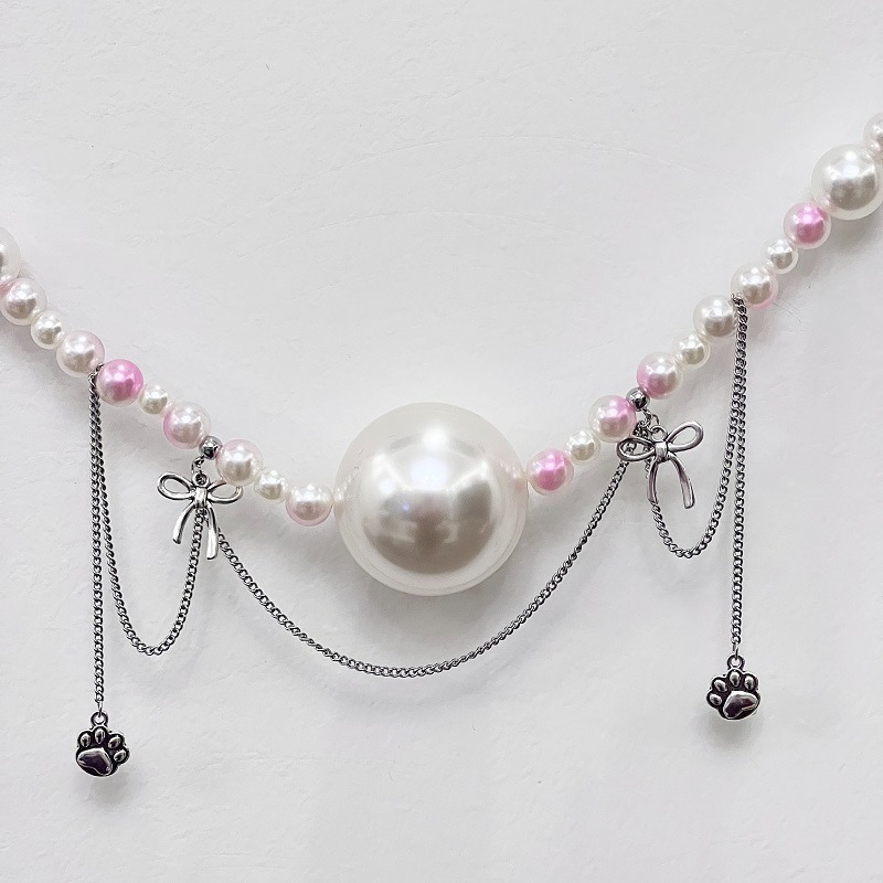 Elegant pearl necklace with charms, featuring a large white pearl and pink accents.