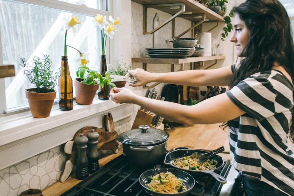 vrouw voor kookplaat met bladeren van bloem