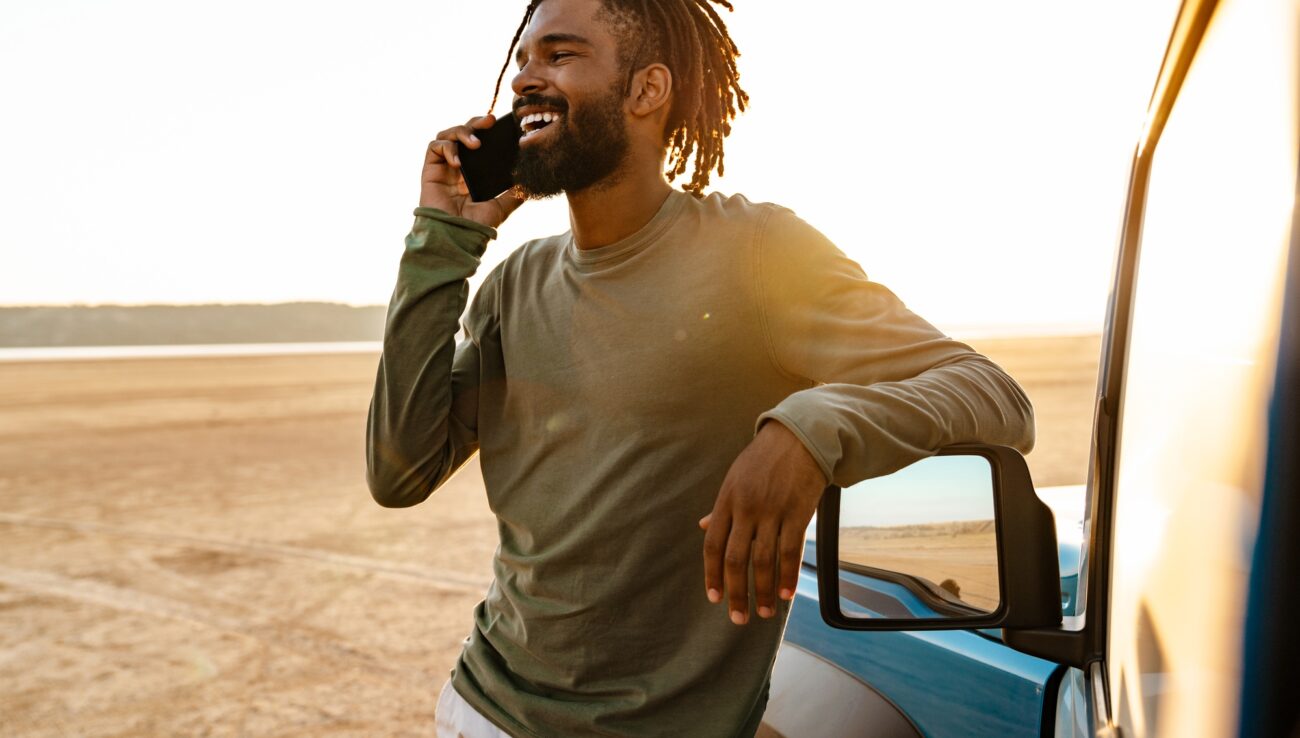 Image of african american man talking on mobile phone while travelling