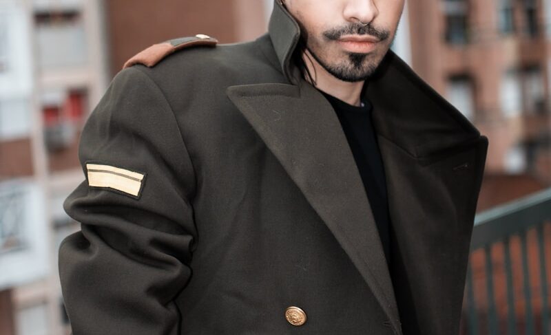 a man with black hair and a beard wearing a coat