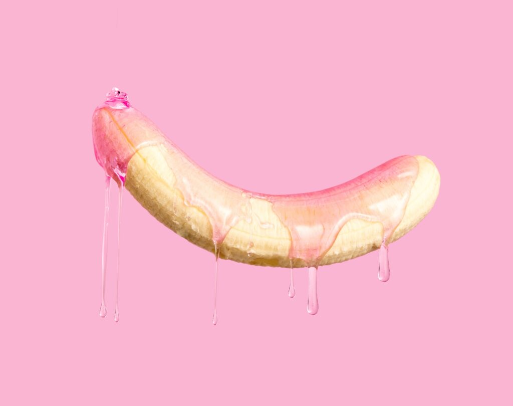 Skalad banan som droppar rosa gelé på rosa bakgrund.