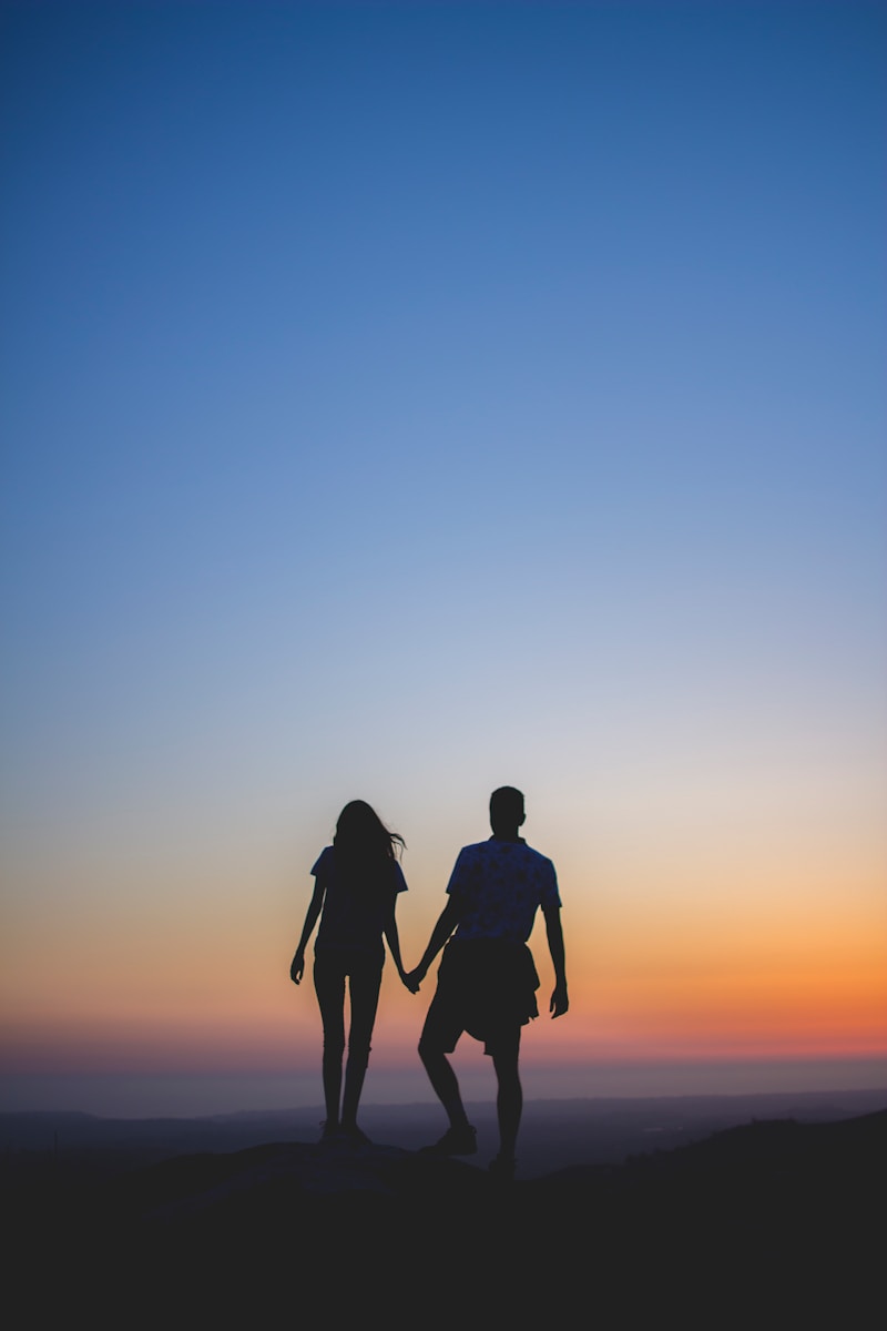 man en vrouw die handen in silhouetfotografie houden