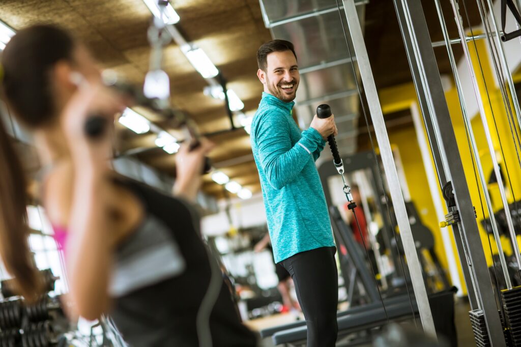 Ungt par tränar bodybuildingövningar i ett modernt gym