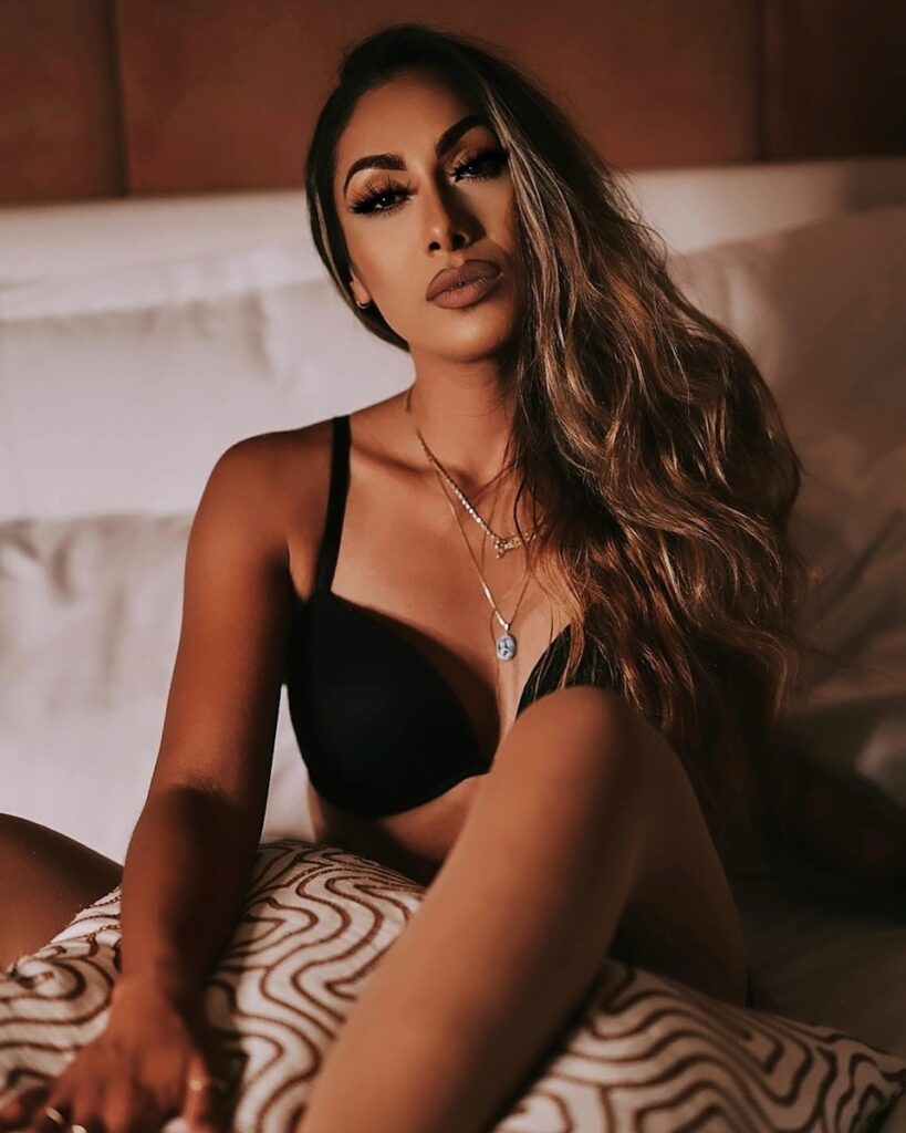 a woman sitting on a bed wearing a black bra