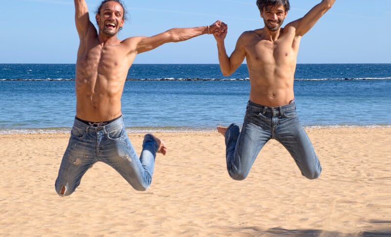 two man jumping above brown beach sand